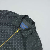 Green patterned jacket with a Louis Vuitton tag on a light gray background